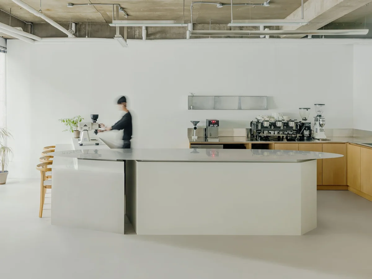 A barista works behind the pale curved counter at Identity Coffee Lab on Donggyo-ro.