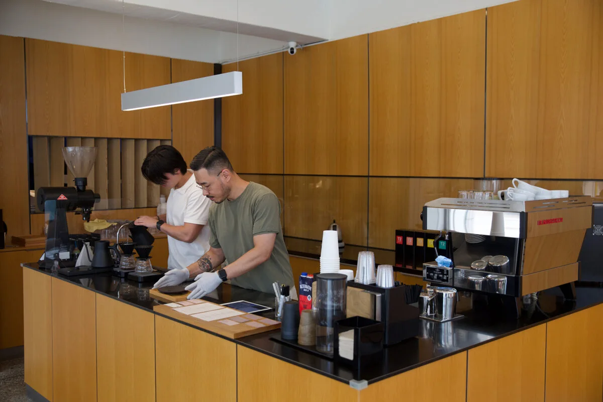 Two baristas preparing coffee behind the wooden counter at John Small Roastery in Yonggang-dong.