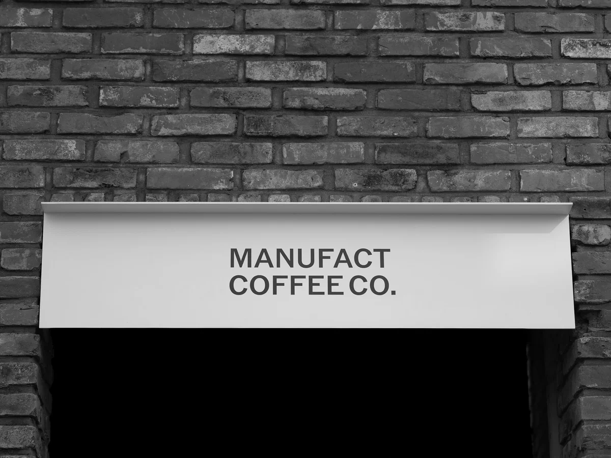 Black-and-white photograph of the MANUFACT COFFEE CO. sign above a brick-framed doorway, used for the official Seochon branch section.