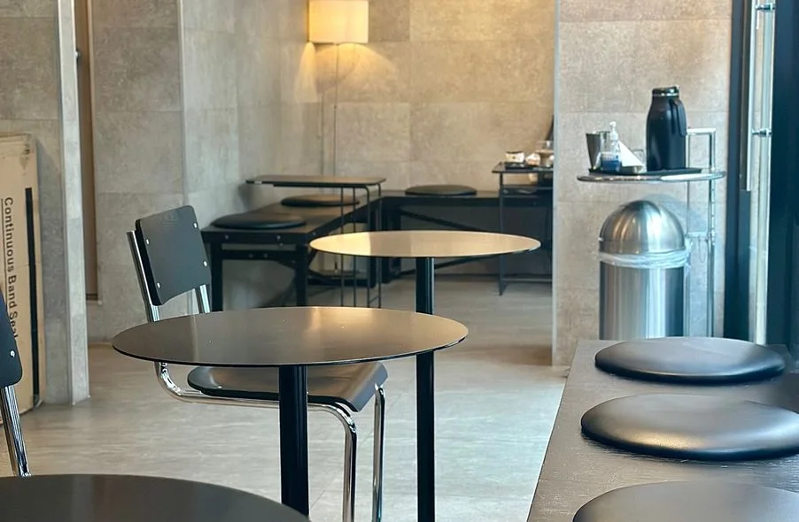 Round black tables and the coffee counter inside Maven Coffee Roasters Sangam.