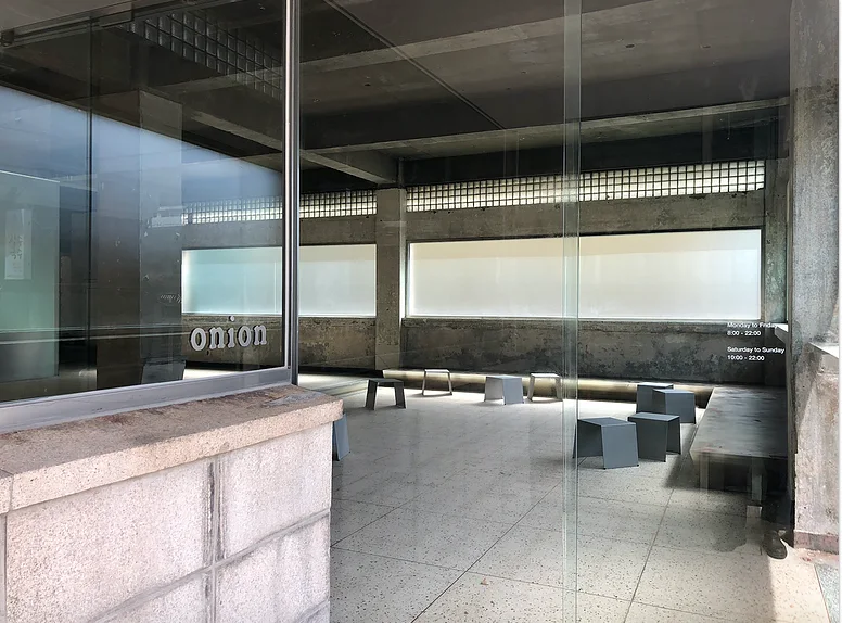 Spacious concrete interior and stone benches beneath Onion signage at the Mia branch.